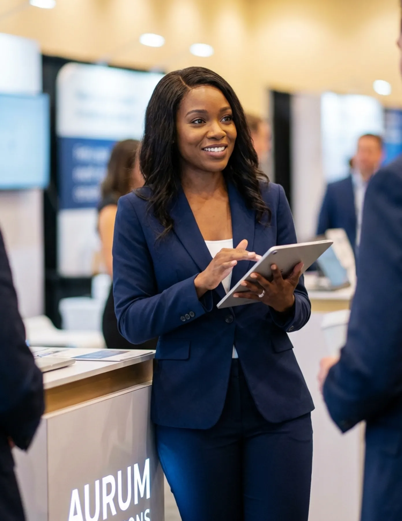 Professional conference staff member using a tablet to assist attendees at a trade show or corporate event booth