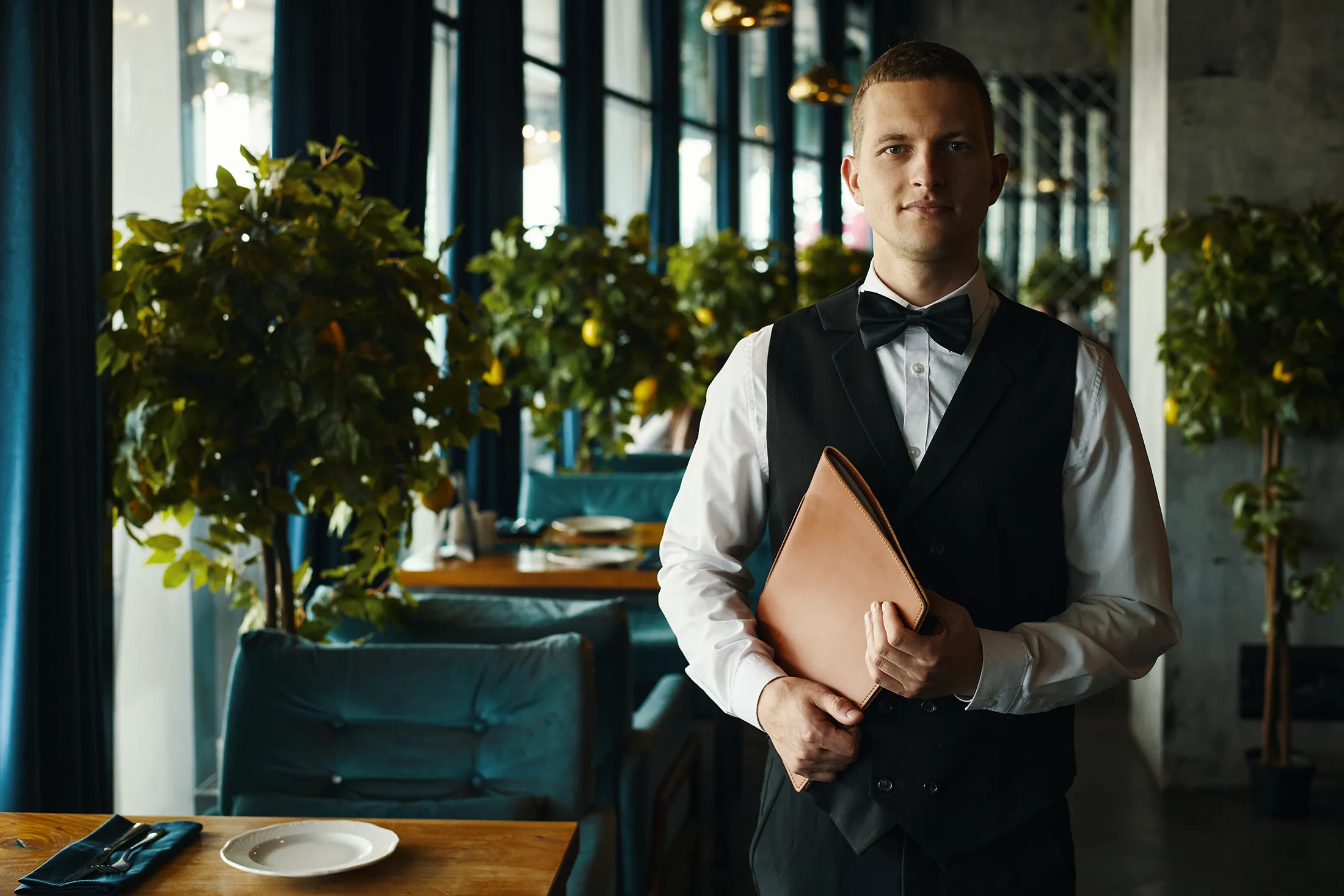 Portrait of Young Adult Caucasian Man Standing in Restaurant Holding Folder