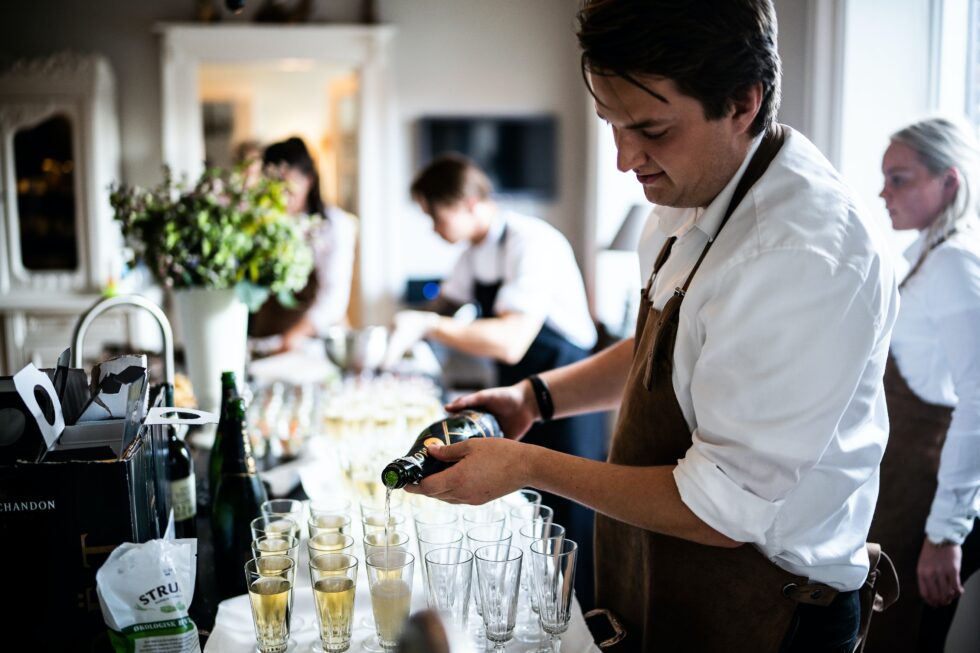 Professional catering staff member pouring champagne glasses for guests at an upscale private event in New York or Chicago