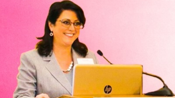 Karen DiPeri, President of HMG+ delivering a talk on stage at a function