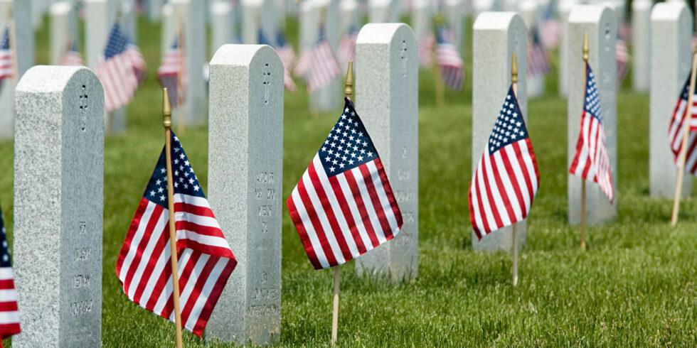 Rows of American flags placed at military gravestones at a national cemetery honoring fallen veterans on Memorial Day