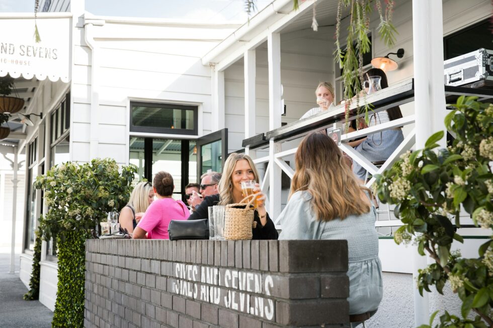 Guests enjoying drinks and socializing at a lively outdoor bar and restaurant patio staffed by professional hospitality staff
