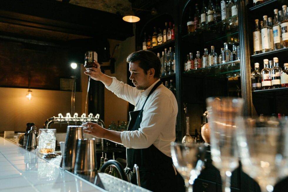 Skilled professional bartender pouring a craft cocktail at an upscale bar for a private event or corporate function in New York