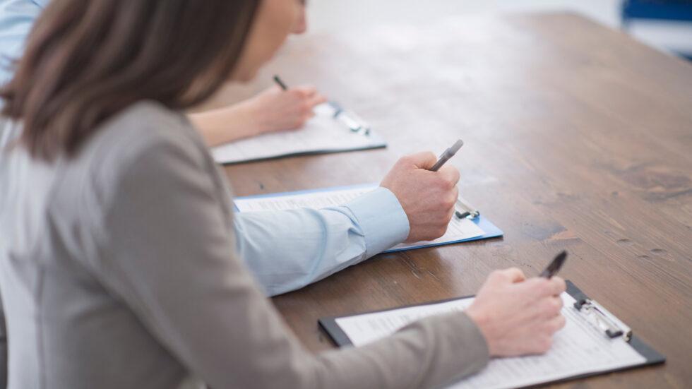 Hospitality professionals completing paperwork during a professional staff vetting and recruitment assessment process at HMG+