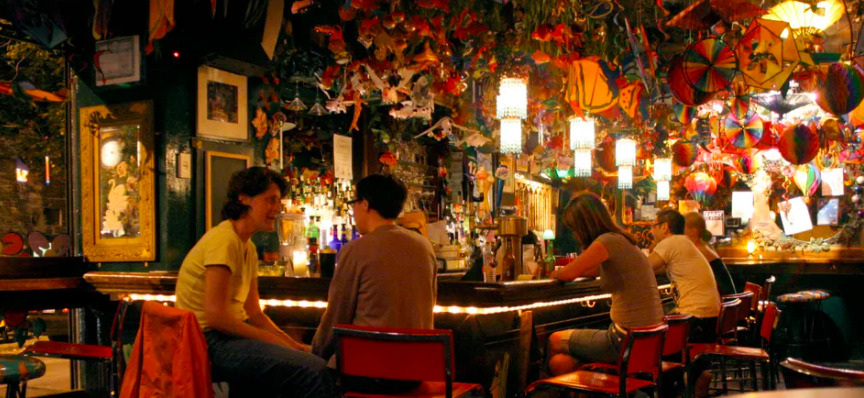 People socializing at a colorful bar with festive decorations and warm lighting