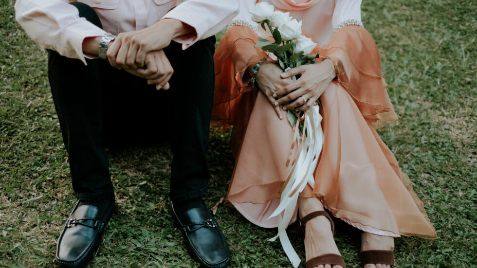 Newly weds sitting on grass after their backyard wedding. Catering by HMG+